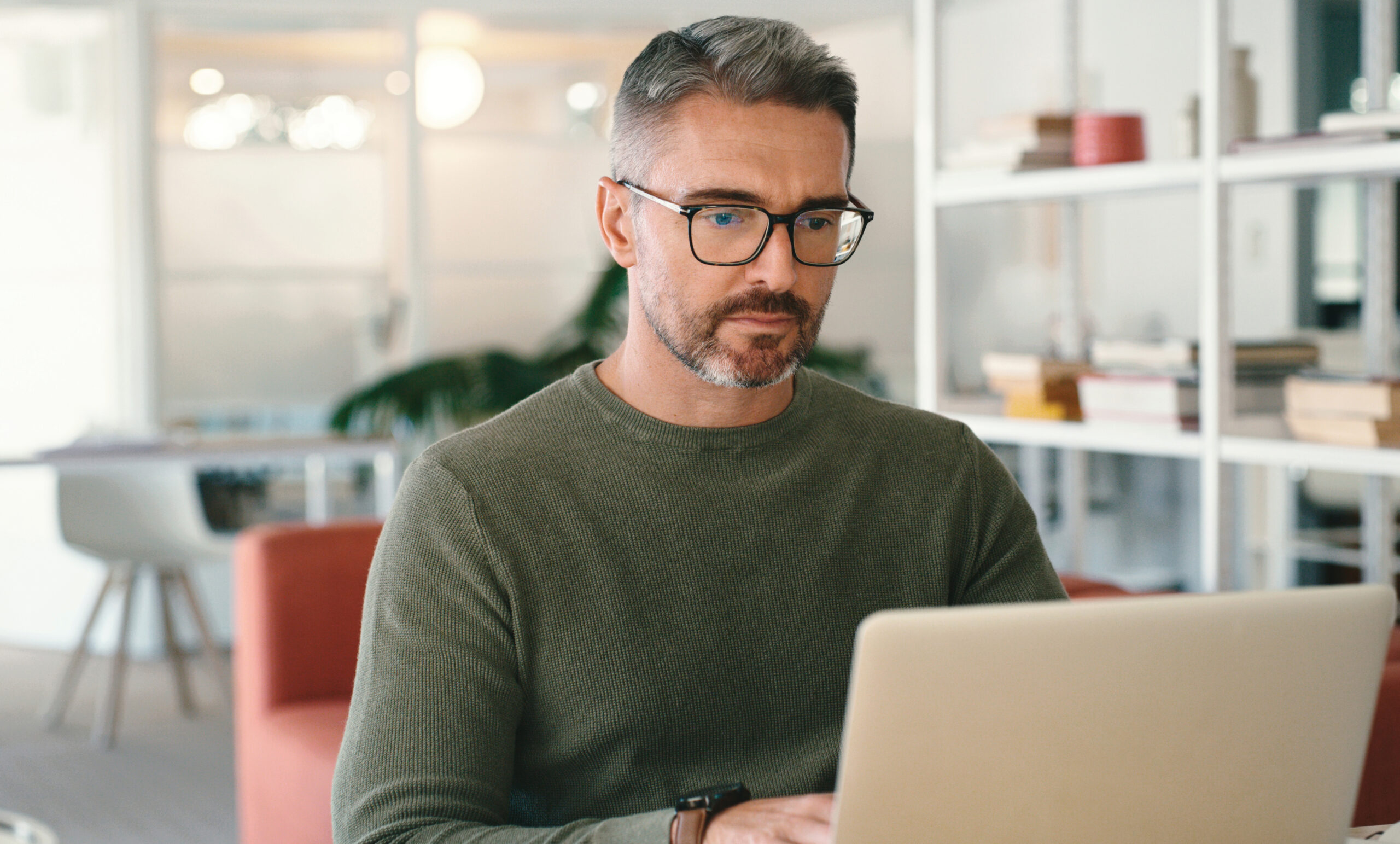Serious man on laptop for business startup, website review and email management in office workspace. Mature tech worker, person or boss reading online report on computer software for career planning